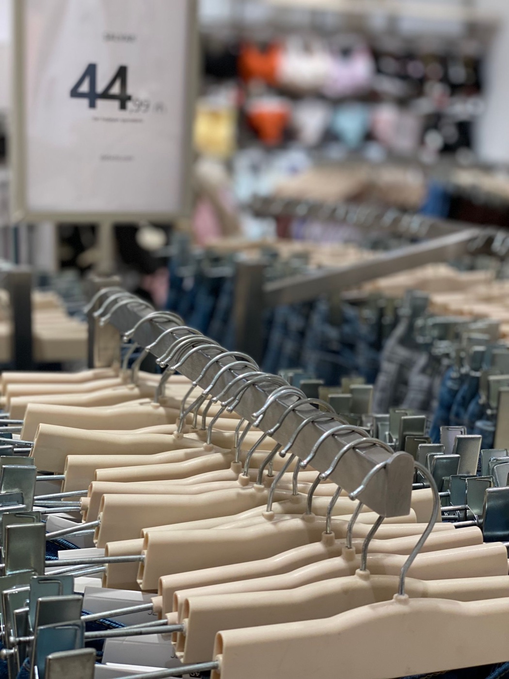 Rows of clip hangers on a mass-market denim floor with a 44.99 price sign hanging above them
