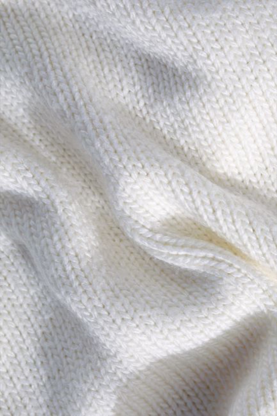 Macro close-up of soft white fine-gauge knit fabric draped in gentle folds